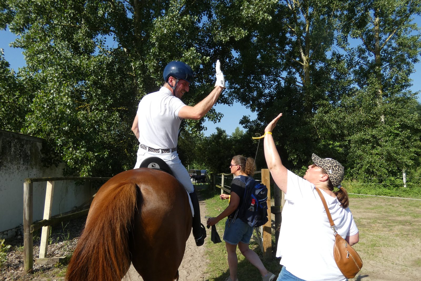 A rider leaning down from the saddle to high-five supporters after a test